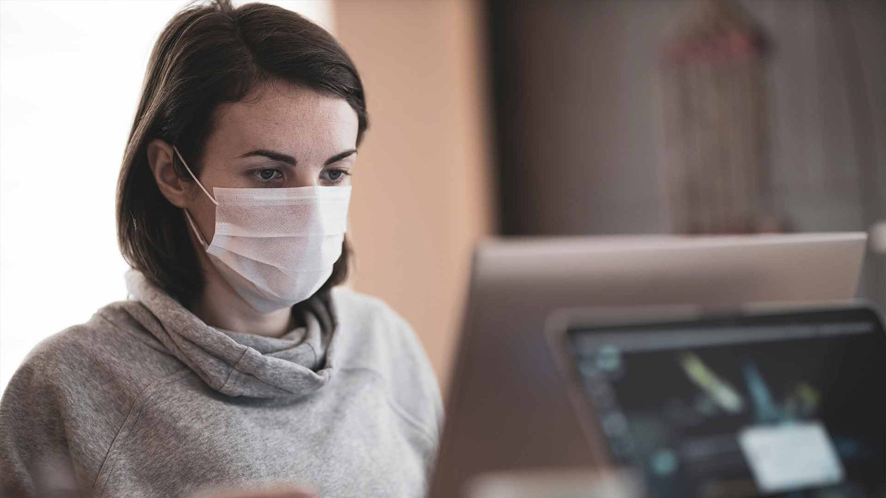 Person with face mask using computer
