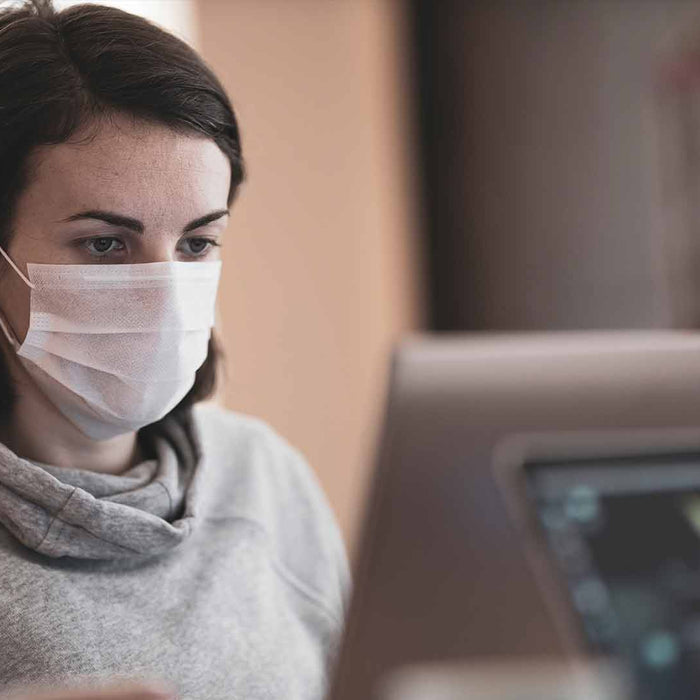 Person with face mask using computer